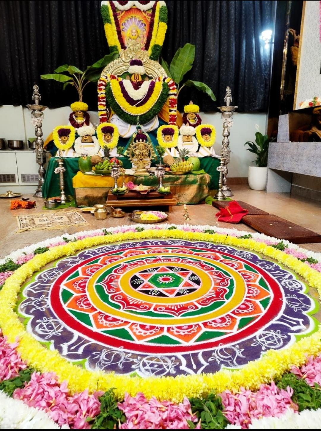 Grand circular floral rangoli and divine altar alankara for auspicious ceremonies